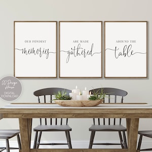 Könnte beinhalten: Drei gerahmte Kunstdrucke mit den Sätzen "Our Fondest Memories", "Are Made Gathered" und "Around the Table" in schwarzer Schrift. Die Drucke befinden sich über einem Esstisch aus Holz mit Stühlen.