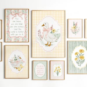 May include: A collection of framed art prints featuring watercolor illustrations of ducks, flowers, and inspirational quotes. The color palette includes soft pinks, yellows, and greens, with gingham and striped backgrounds. The prints are in wooden frames.