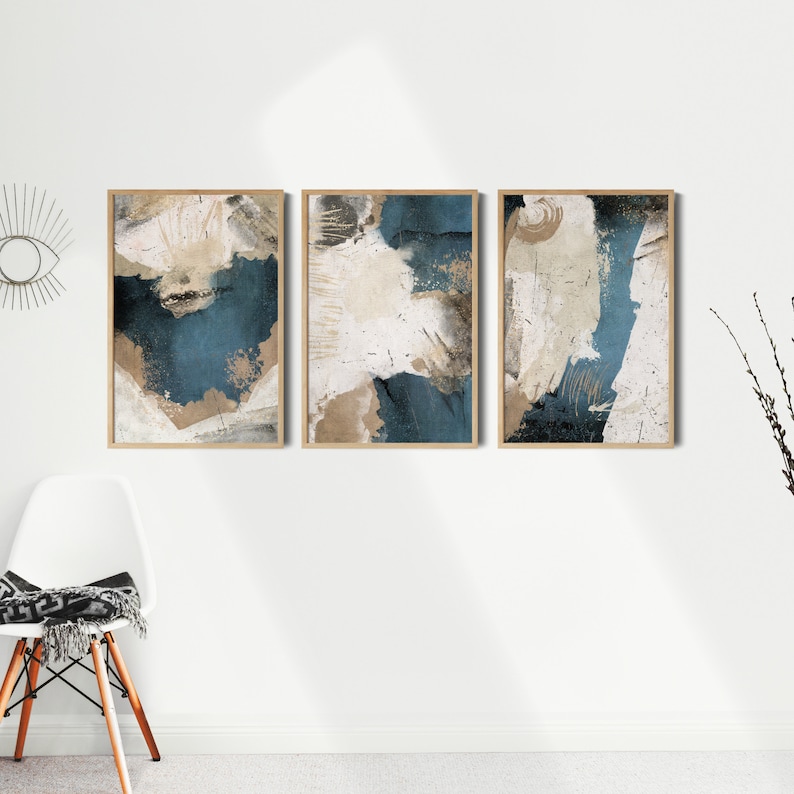 May include: Three abstract art prints with a blue, white, and brown color scheme. The prints are framed in wood and have a distressed, textured look.