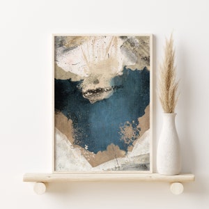 May include: Abstract art print in a white frame with a blue, beige, and white color scheme. The print features a textured background with splattered paint.