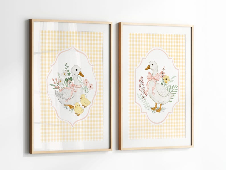 May include: Two framed prints featuring watercolor illustrations of geese. One print shows a goose with two chicks and flowers, the other shows a goose with a pink bow and flowers. Both are set against a yellow gingham background.