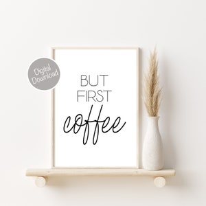 Puede incluir: Una impresi&oacute;n de arte de pared imprimible en blanco y negro con el texto "BUT FIRST COFFEE" en un estilo de caligraf&iacute;a moderno. La impresi&oacute;n est&aacute; enmarcada y se muestra en un estante con un jarr&oacute;n de hierba de la pampa seca.