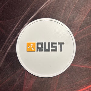 May include: A white round sticker with a black and orange logo that says "RUST".