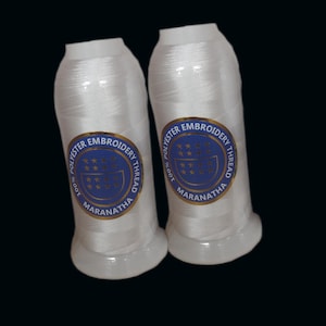 May include: Two spools of white 100% polyester embroidery thread with blue and gold labels that read "100% Polyester Embroidery Thread Maranatha".
