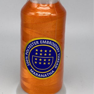 May include: A spool of orange embroidery thread with a white label that reads "100% Polyester Embroidery Thread Maranatha" with a blue circle containing stars.