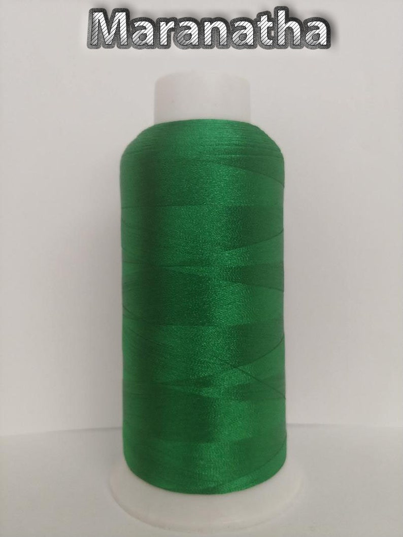 May include: A spool of bright green thread on a white plastic bobbin. The thread is wound tightly and has a smooth, shiny finish.