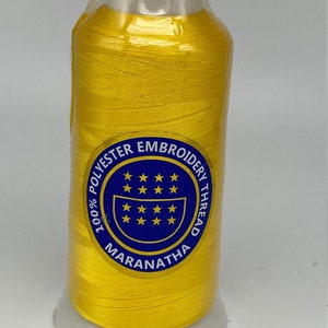 May include: A spool of yellow 100% polyester embroidery thread with a blue label that reads "100% Polyester Embroidery Thread Maranatha".