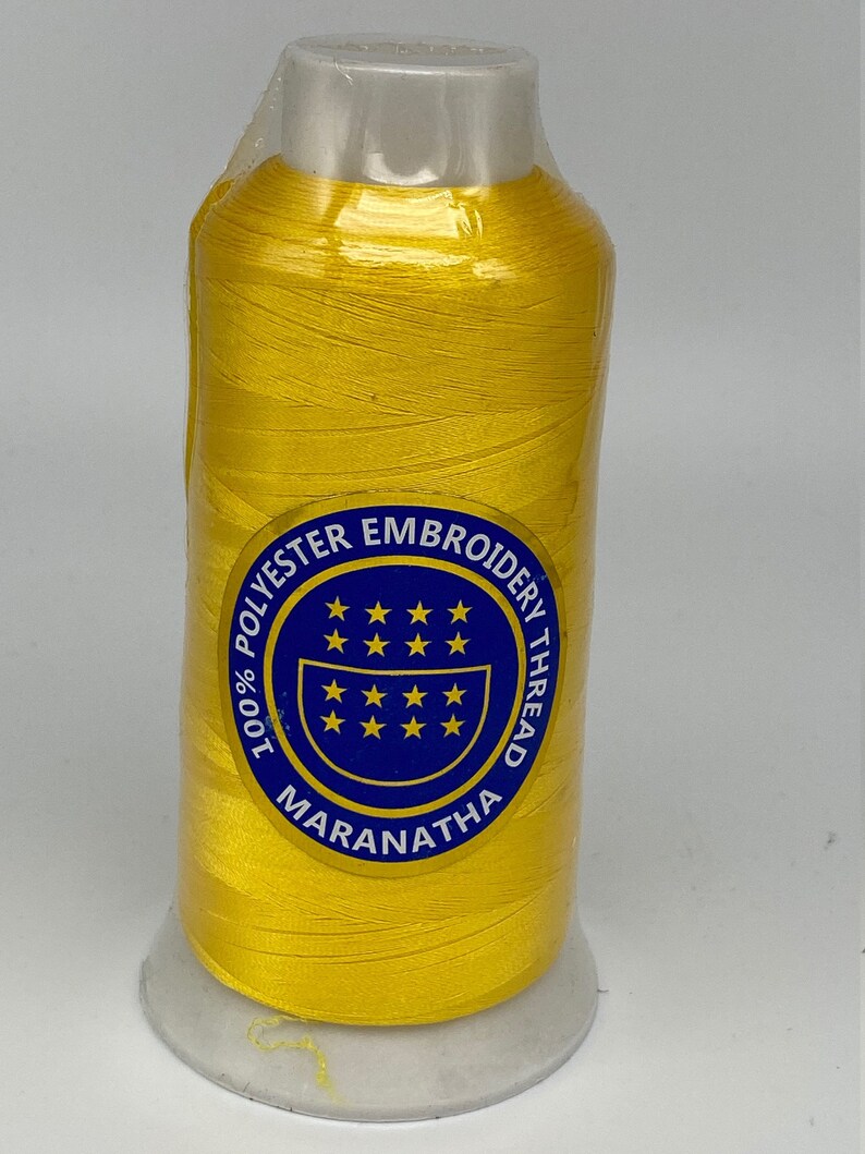 May include: A spool of yellow 100% polyester embroidery thread with a blue label that reads "100% Polyester Embroidery Thread Maranatha".
