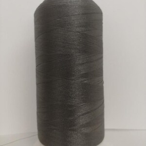 May include: A spool of dark gray thread on a white bobbin. The spool is labeled "Maranatha".