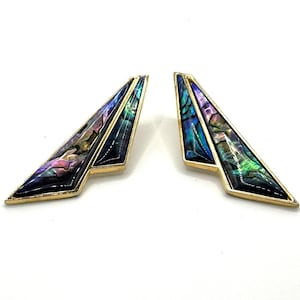May include: A pair of geometric earrings with iridescent abalone shell inlays. The earrings have a gold-tone metal frame and a triangular shape, with a pointed end and a wider base. The abalone shell displays a range of colors, including blue, green, purple, and pink.