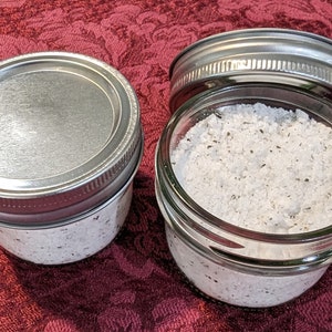 May include: Three glass jars with silver lids filled with a white powder. The jars are on a red floral tablecloth.