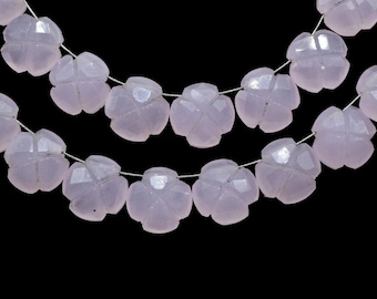 May include: Strands of pale lavender flower-shaped beads against a black background. The beads are faceted, catching the light and creating a sparkling effect. These beads are strung on a thin, silver-colored wire.