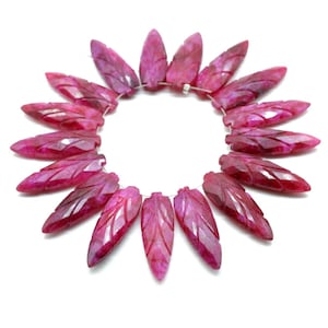 May include: A strand of carved gemstone beads in a leaf shape. The beads are a deep magenta color with carved details. The beads are strung together in a circular pattern against a white background.