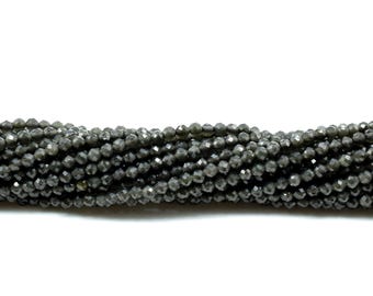May include: Strands of faceted, dark gray beads. The beads have a multifaceted surface, reflecting light. The beads are strung together, creating a continuous line. Ideal for jewelry making or crafting projects.