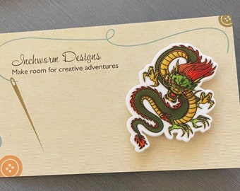 May include: A white card with the text "Inchworm Designs" and "Make room for creative adventures". A green, yellow, and red dragon sticker is on the card.