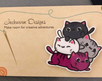 May include: A stack of four cute cartoon cats in different colors and poses. The cats are stacked on top of each other, with the largest cat on the bottom and the smallest cat on top. The cats are all smiling and have big eyes. The text "Inchworm Designs" and "Make room for creative adventures" is visible on the background.