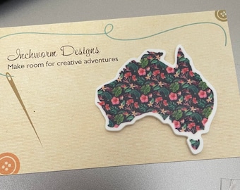 May include: A white card with the text "Inchworm Designs" and "Make room for creative adventures". A needle and thread are in the background. A white outline of Australia with a floral pattern is on the card.