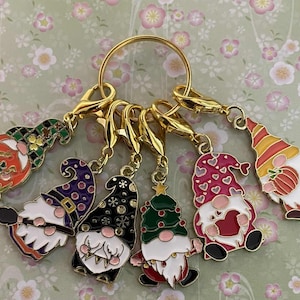 May include: A selection of colourful gnome charms with gold-tone clasps and a large ring. Each charm features a unique design, including a Christmas tree, hearts, and a pumpkin. The gnomes have white beards and various hat styles.