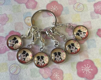May include: A set of seven silver-toned charms with a dog design. Each charm features a black and white dog illustration on a pink heart background, attached to a keyring and clasps.