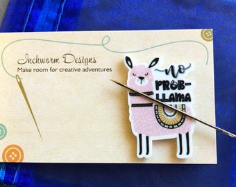 May include: A pink llama with a black and white patterned saddle and the text "no prob-llama" on a wooden card with the text "Inchworm Designs Make room for creative adventures".