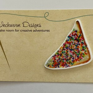 Può includere: Una carta bianca con sfondo marrone e un'immagine colorata di una fetta di pane con codette. La carta ha il testo "Inchworm Designs" e "Make room for creative adventures".