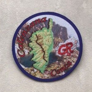 Peut inclure: Un écusson rond bleu et blanc brodé avec un contour vert d'une chaîne de montagnes et un logo "GR" rouge. Le texte "Calabria" et "Sentiero" sont brodés en rouge sur l'écusson.