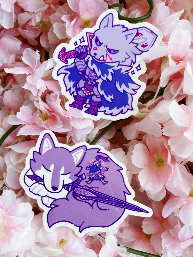 May include: Two stickers featuring cartoon wolf characters. One wolf is a warrior with a sword, wearing armor and a cape. The other wolf is sleeping, with a sword and a small figure on its back. The stickers are shades of purple and blue.