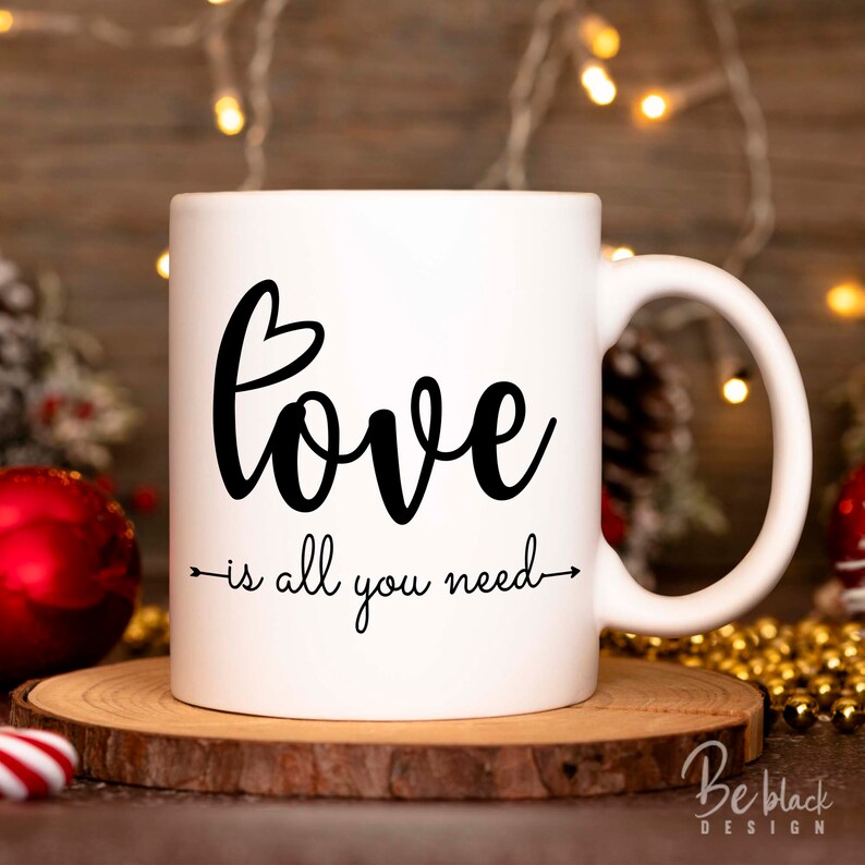 May include: White ceramic mug with black text that reads "love is all you need" with a small heart above the word "love".