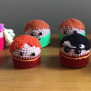 Puede incluir: Un conjunto de diez personajes de crochet, cada uno con un diseño y color diferente. Los personajes llevan todos sombreros y tienen diferentes expresiones faciales.