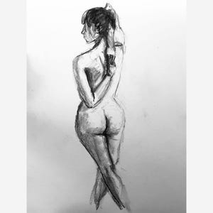 May include: A charcoal sketch depicting a nude figure from behind. The arms are crossed behind the back, and the legs are crossed at the ankles. The drawing uses shades of grey and black, emphasising form and shadows, creating a sense of depth.