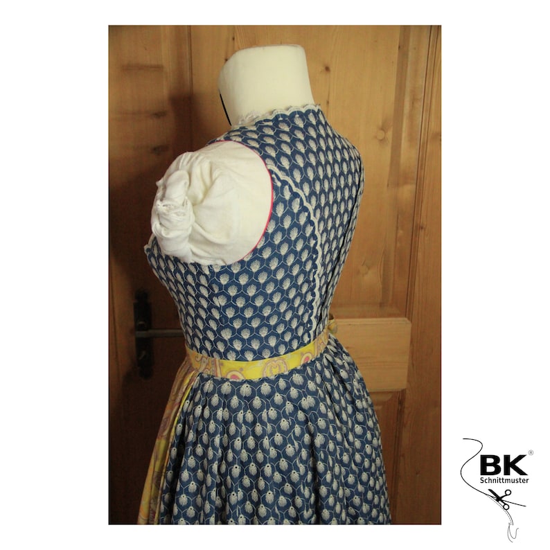 Peut inclure: Une robe traditionnelle bavaroise bleue et blanche &agrave; motif avec une ceinture jaune &agrave; motif floral. La robe a une bordure en dentelle blanche au niveau du d&eacute;collet&eacute; et une bordure rouge autour des emmanchures.