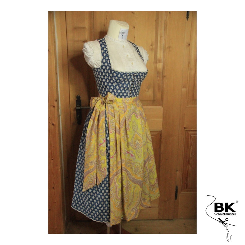 Peut inclure: Une robe traditionnelle bavaroise bleue et jaune avec un chemisier blanc et une ceinture jaune. La robe est orn&eacute;e d'une dentelle blanche et d'un motif floral.