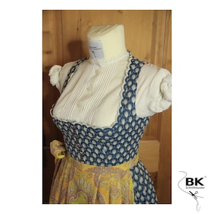 Peut inclure: Une robe traditionnelle bavaroise bleue et blanche avec une jupe &agrave; imprim&eacute; floral jaune et bleu. Le corsage a un bord festonn&eacute; et une blouse blanche avec un col &agrave; volants.