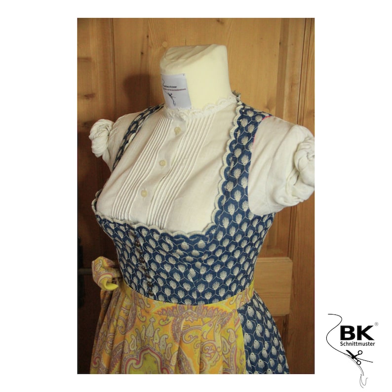 Peut inclure: Une robe traditionnelle bavaroise bleue et blanche avec une jupe &agrave; imprim&eacute; floral jaune et bleu. Le corsage a un bord festonn&eacute; et une blouse blanche avec un col &agrave; volants.