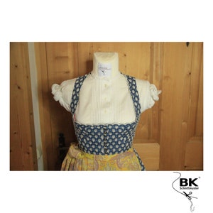 Peut inclure: Un corsage de dirndl &agrave; motifs bleus et blancs avec un chemisier blanc et une jupe jaune. Le corsage a un bord festonn&eacute; et une rang&eacute;e de boutons sur le devant. La jupe a un motif cachemire. L'image comprend le texte "BK Schnittmuster".