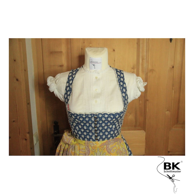 Peut inclure: Un corsage de dirndl &agrave; motifs bleus et blancs avec un chemisier blanc et une jupe jaune. Le corsage a un bord festonn&eacute; et une rang&eacute;e de boutons sur le devant. La jupe a un motif cachemire. L'image comprend le texte "BK Schnittmuster".