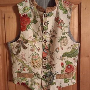 May include: A white linen vest with a floral pattern. The vest has a mandarin collar and a cork trim. It has a button closure and two pockets.