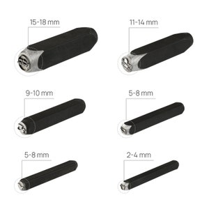 May include: Set of six black metal letter stamping tools with different sizes, ranging from 2-4 mm to 15-18 mm. Each tool has a silver metal head with a design.