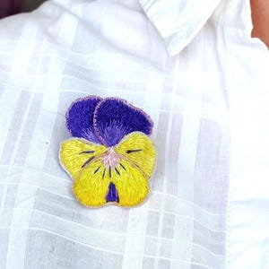 Geborduurde viooltjesbroche (blauw en geel).  Handgemaakte vilten bloemspeld voor tassen, blazer