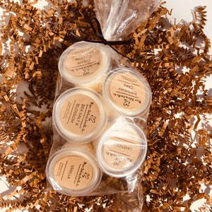 May include: A clear plastic bag filled with six small jars of candle wax. The jars are labeled with the scents: "Birthday Cake", "Sea Salt & Blossom", "Lavender", "Vanilla", "Clean Cotton".