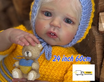 May include: A 24 inch (60cm) reborn doll wearing a yellow and blue knitted dress and a blue knitted hat. The doll is holding a small teddy bear with a Ukrainian flag heart.