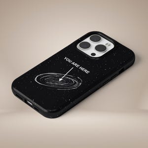 May include: Black phone case with a galaxy design and the text "You are here" with an arrow pointing to a spiral galaxy.