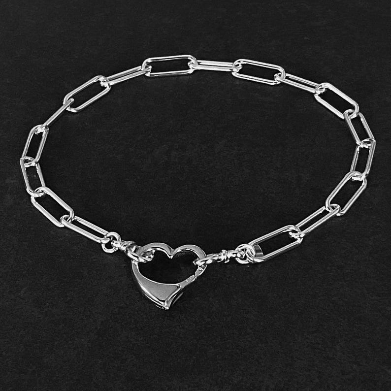May include: A silver chain bracelet with a heart-shaped clasp.