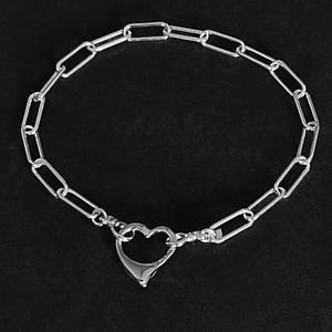 May include: A silver chain bracelet with a heart-shaped clasp.