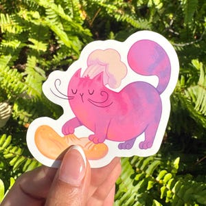 May include: A whimsical sticker featuring a pink cat with a chef's hat, interacting with a slice of orange fruit. The cat has long whiskers and a purple tail. The sticker is set against a backdrop of green foliage.