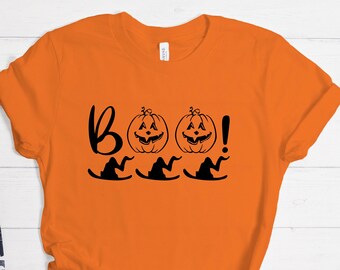 May include: Orange t-shirt with a black graphic design that says "Boo!" with three witch hats and two pumpkin faces.