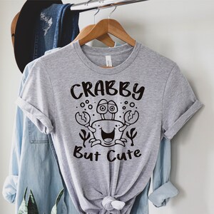 May include: Gray t-shirt with a black cartoon crab and the text "Crabby But Cute".