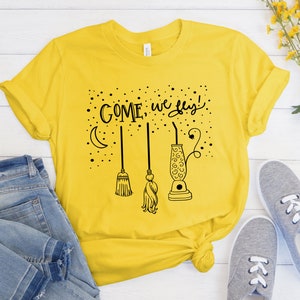 May include: Yellow t-shirt with a black graphic that says "Come, we fly!" with a crescent moon, a broom, and a lava lamp.