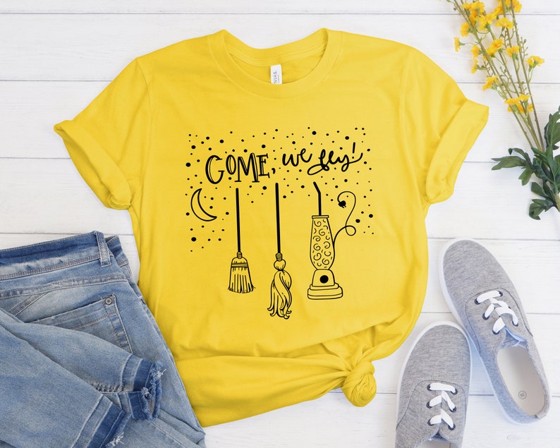 May include: Yellow t-shirt with a black graphic that says "Come, we fly!" with a crescent moon, a broom, and a lava lamp.