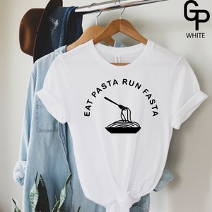 Może przedstawiać: Biała koszulka z czarnym napisem "Eat Pasta Run Fasta" i grafiką widelca i spaghetti w misce.